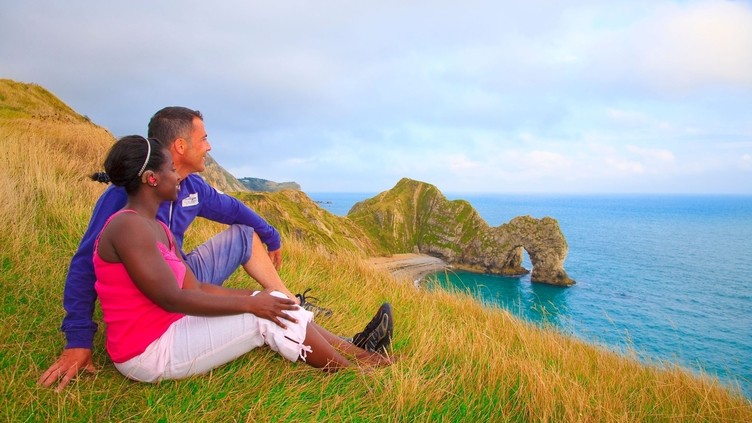 Couple sat on the grass looking out to the sea